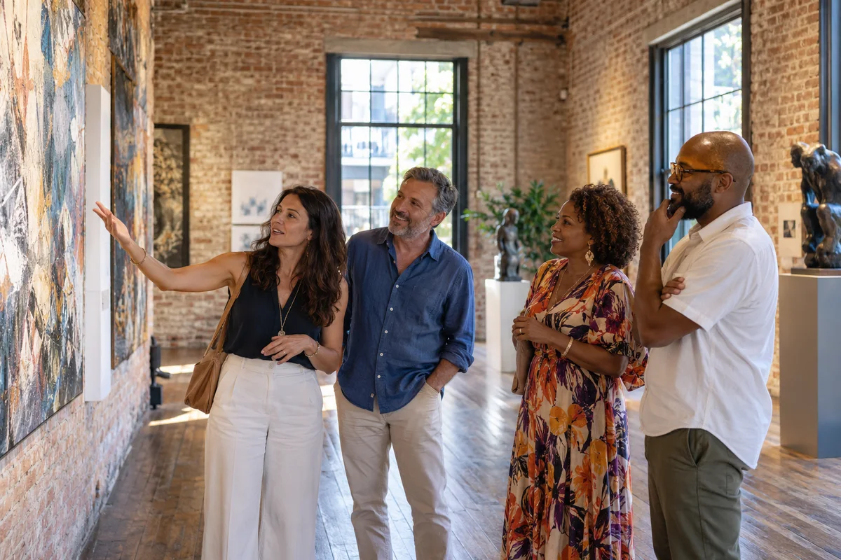 Four adult friends, two men and two women, viewing art in a New Orleans neighborhood gallery, brick walls and tall old windows